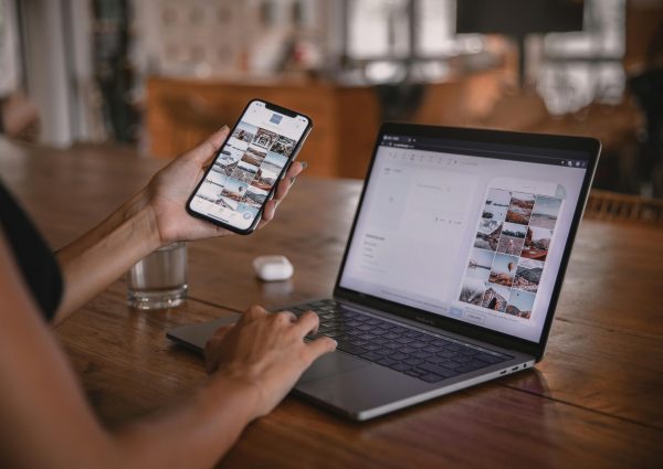 Woman edits social media content on phone and laptop at a cafe in Bali.